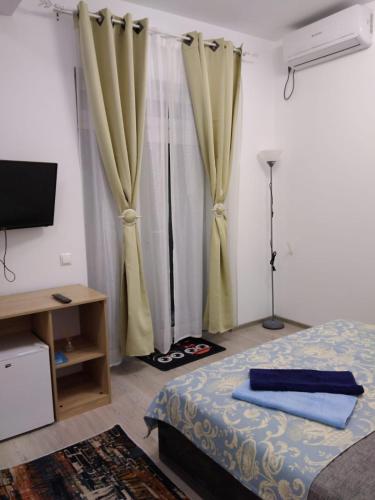 a bedroom with a bed and a television and curtains at Casa KIM in Eforie Nord