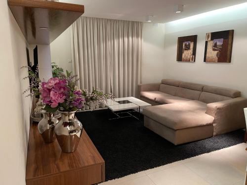 a living room with a couch and a table with flowers at Deluxe Apartment with pool in the heart of St Pauls Bay in St Paul's Bay