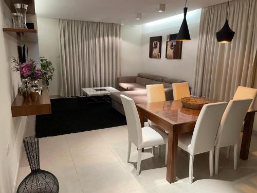 a living room with a wooden table and white chairs at Deluxe Apartment with pool in the heart of St Pauls Bay in St Paul's Bay