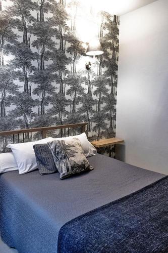 a bed with two pillows in a bedroom with a wallpaper at Hôtel Saint Florent in Orange