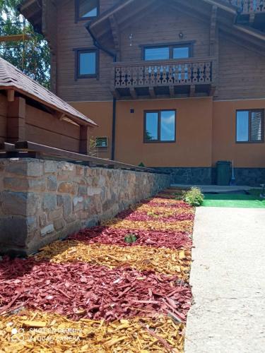 a house with a retaining wall and a pile of leaves at VIOLETTA in Slavske