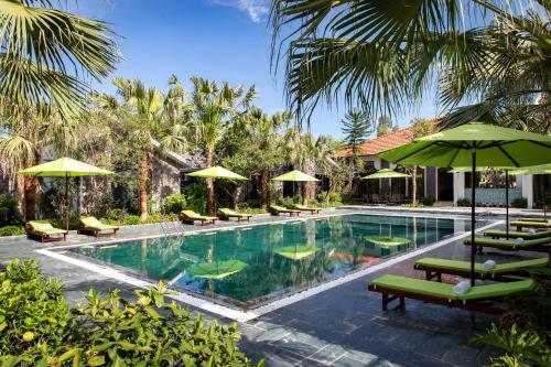 una piscina con sombrillas y sillas verdes en Bai Dinh Riverside Resort & Spa, en Ninh Binh