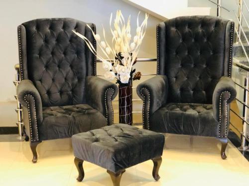 two black chairs and a ottoman in a room at Hotel Silver Oaks in Narān