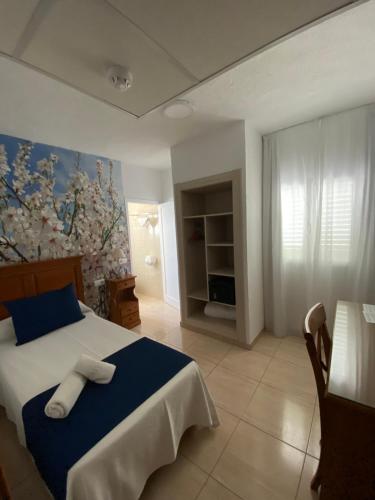 a bedroom with a bed and a painting on the wall at Hostal Mar y Huerta in Es Cana