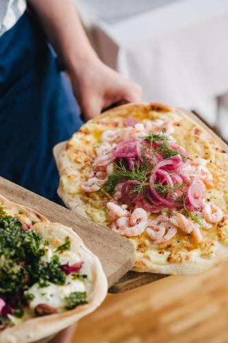 a person is holding two pizzas on a table at Björholmen Hotell & Restaurang in Björholmen