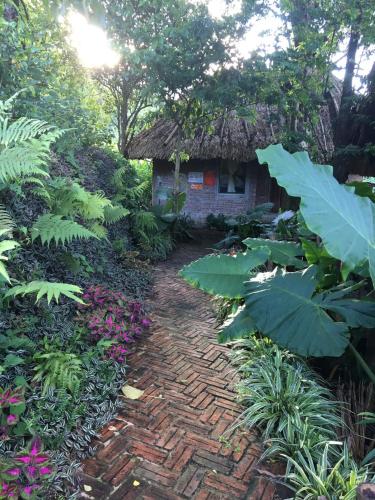 a brick path leading to a house with a thatch roof at Pu Luong Ecocharm in Hương Bá Thước