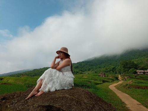 a woman in a white dress sitting on a rock at Pu Luong Ecocharm in Hương Bá Thước