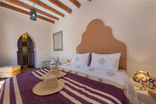 Un dormitorio con una cama grande con dos sombreros. en Absolu Beldi Essaouira, en Essaouira