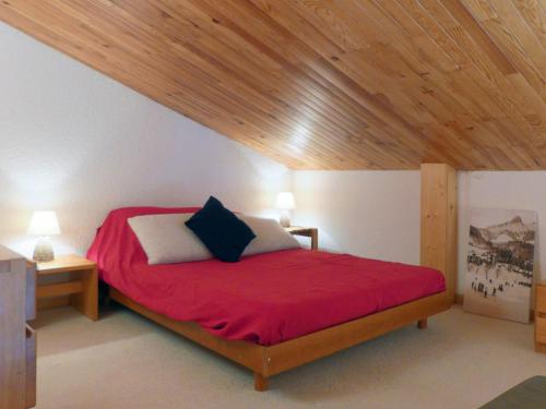 a bedroom with a red bed with a wooden ceiling at Appartement Méribel, 2 pièces, 6 personnes - FR-1-182-59 in Méribel