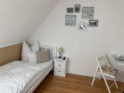 ein weißes Schlafzimmer mit einem Bett und einem Stuhl in der Unterkunft Guest House Dommitzsch in Dommitzsch