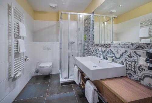 a bathroom with a sink, toilet and bathtub at JUFA Hotel Salzburg City in Salzburg