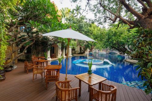 an outdoor patio with a table and chairs and a pool at Khum Phaya Resort & Spa Boutique Collection in Chiang Mai