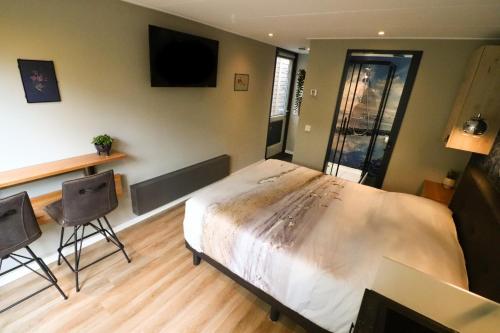 a bedroom with a large bed and two chairs at De Monarchvlinder in Den Burg