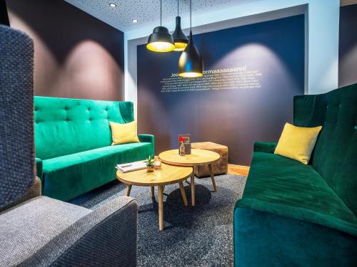 a living room with a green couch and a table at JUFA Hotel Salzburg in Salzburg