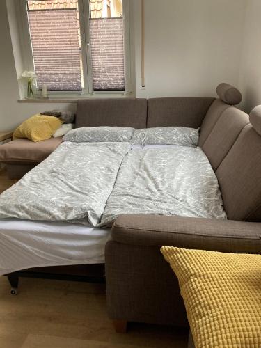 a bed in a room with a couch and two windows at Ferienwohnung am Hühnerberg in Buchbrunn