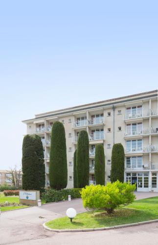 a large apartment building with trees in front of it at Résidences LES HAUTES PLAINES in Gréoux-les-Bains