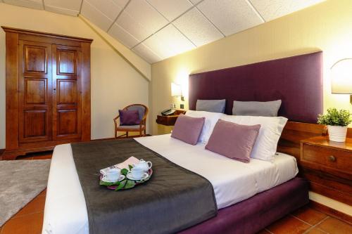 una camera da letto con un grande letto con un piatto di fiori di Corsaro Etna Hotel&SPA a Nicolosi
