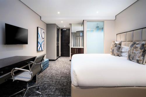 a hotel room with a bed and a desk and a tv at Premier Hotel Umhlanga in Durban