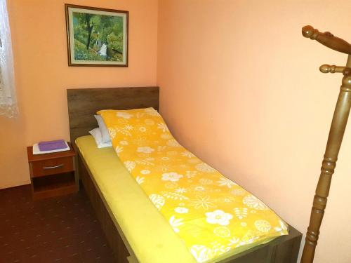 a small bedroom with a bed with a yellow blanket at Saraj Guest House in Kulen Vakuf