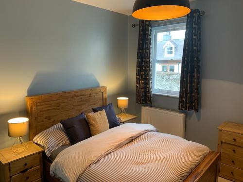 a bedroom with a bed with two lamps and a window at Skippers Retreat (with free doorstep parking) in North Berwick