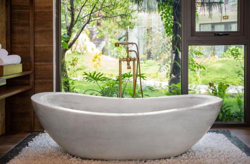a white bath tub in a bathroom with a window at Bai Dinh Riverside Resort & Spa in Ninh Binh