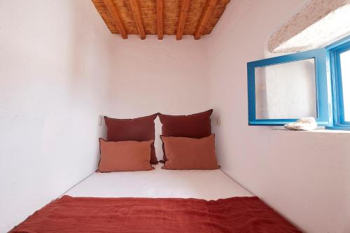 a bedroom with a bed with pillows and a window at Kimolos View in Kimolos