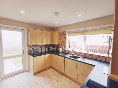a kitchen with wooden cabinets and a large window at 21 Ivorhill in Stornoway