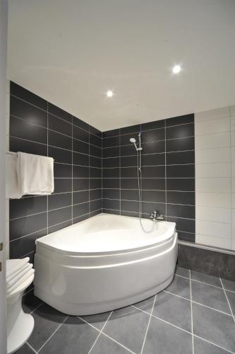 La salle de bains est pourvue d'une baignoire blanche et de carrelage noir. dans l'établissement Le Clos Fleuri - Maison Vigier, à Maringues