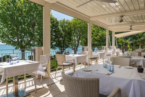 a restaurant with white tables and chairs and the ocean at Villa Rosa Hotel Desenzano in Desenzano del Garda