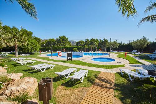 un parque con sillas blancas y una piscina en Alannia Costa Dorada, en Platja de l’Almadrava