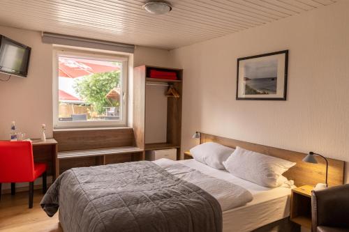 Schlafzimmer mit einem Bett und einem Fenster in der Unterkunft Hotel zur Post Ochsendorf in Königslutter am Elm