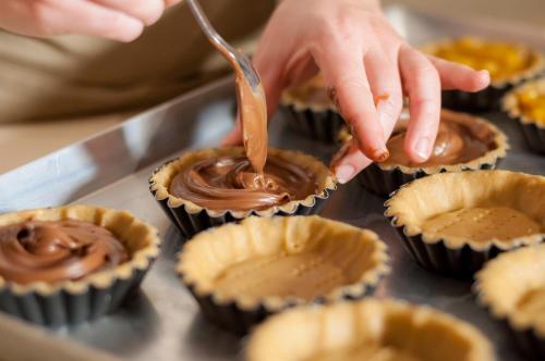 a person sprinkling chocolate on top of cupcakes at PALAZZO FRANGIPANE in Salve