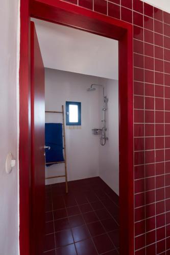 a bathroom with a shower and a red door at Kimolos View in Kimolos