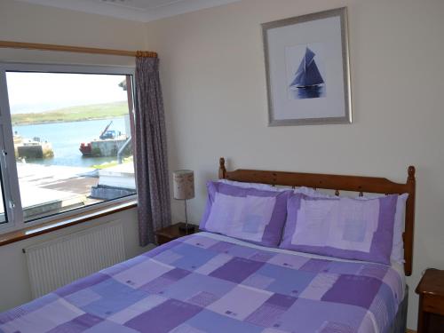1 dormitorio con cama morada y ventana en Oliver's Seafood Bar, Bed & Breakfast, en Cleggan