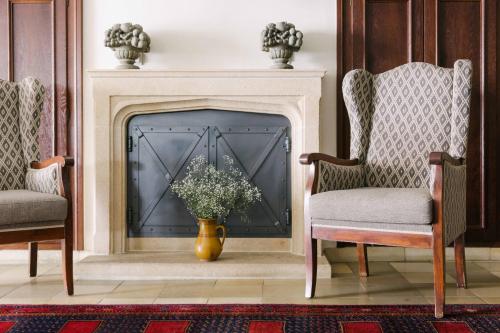 a fireplace with two chairs and a vase of flowers at Hotel Bräu in Zell am Ziller