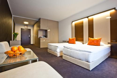 a hotel room with two beds and a bowl of oranges at Platinum Apartments Aparthotel in Poznań