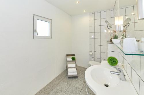 a white bathroom with a sink and a toilet at Hotel zum dicken Baum in Mayen