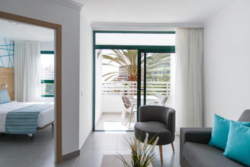 een slaapkamer met een bed, een bank en een stoel bij Alsol Walhalla in Playa del Inglés