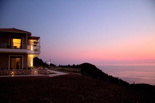 a house on top of a hill at sunset at MELIKIRON LUXURY APARTMENTS in Agios Nikitas