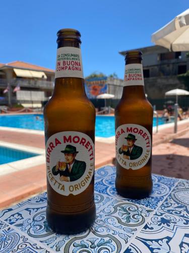 twee flessen bier op een tafel naast een zwembad bij Nuccio's house in Santa Tecla