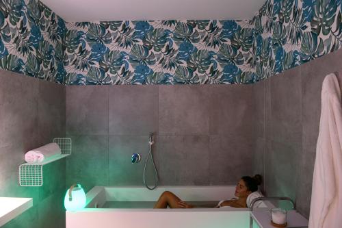 a woman sitting in a bath tub in a bathroom at Seawater Hotel Bio & Beauty Spa in Marsala
