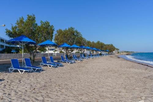 a row of blue chairs and umbrellas on a beach at Kos Palace in Tigaki