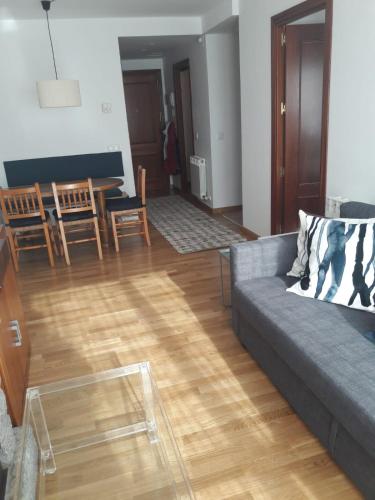 a living room with a couch and a wooden floor at Agradable apartamento con jardín privado en Cerler in Cerler