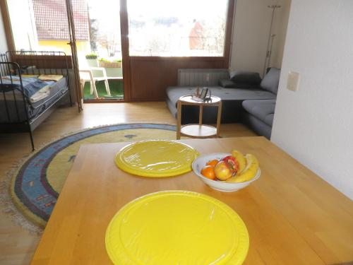 a living room with two yellow plates and a bowl of fruit on a table at Ferienwohnung am Cambomare in Kempten