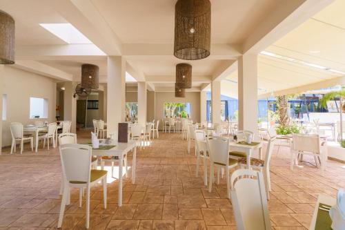 uma sala de jantar com mesas e cadeiras brancas em Kos Palace em Tigaki