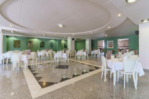 a dining room with white tables and white chairs at Kos Palace in Tigaki