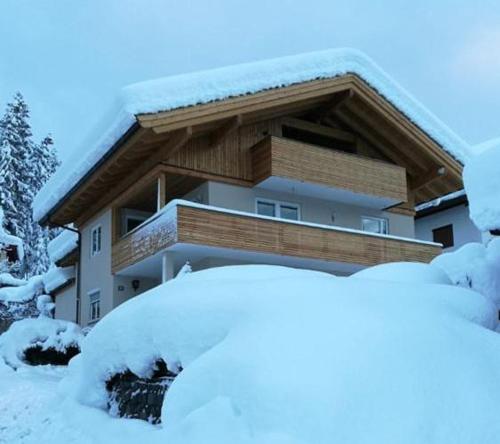 ein Haus ist mit Schnee bedeckt mit schneebedeckten Büschen in der Unterkunft Wittner's in Söll