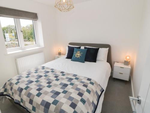 a bedroom with a bed with a blue and white checkered blanket at Dune Retreat in Rhosneigr