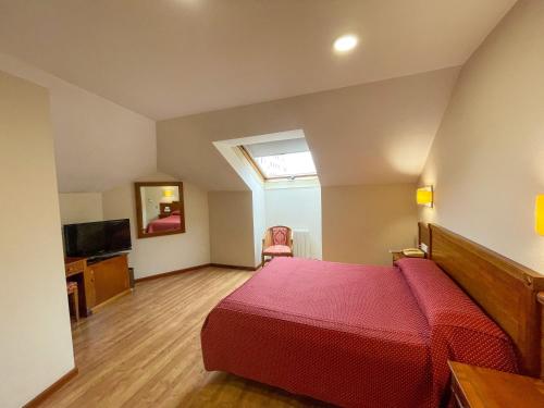 a bedroom with a red bed and a television at Arbeyal in Gijón