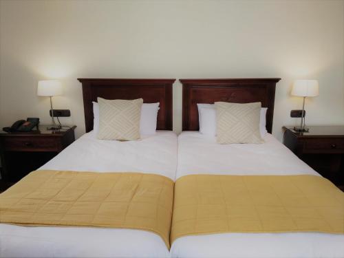 two beds in a bedroom with two nightstands and lamps at Hotel Rural Victoria - La Orotava in La Orotava
